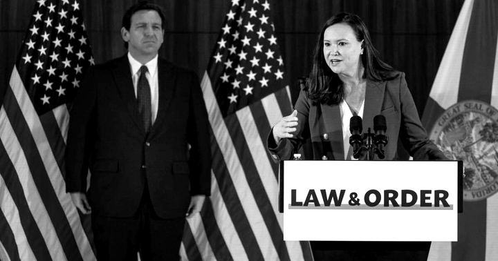Ron DeSantis standing behind Ashley Moody at a podium with a Law and Order sign